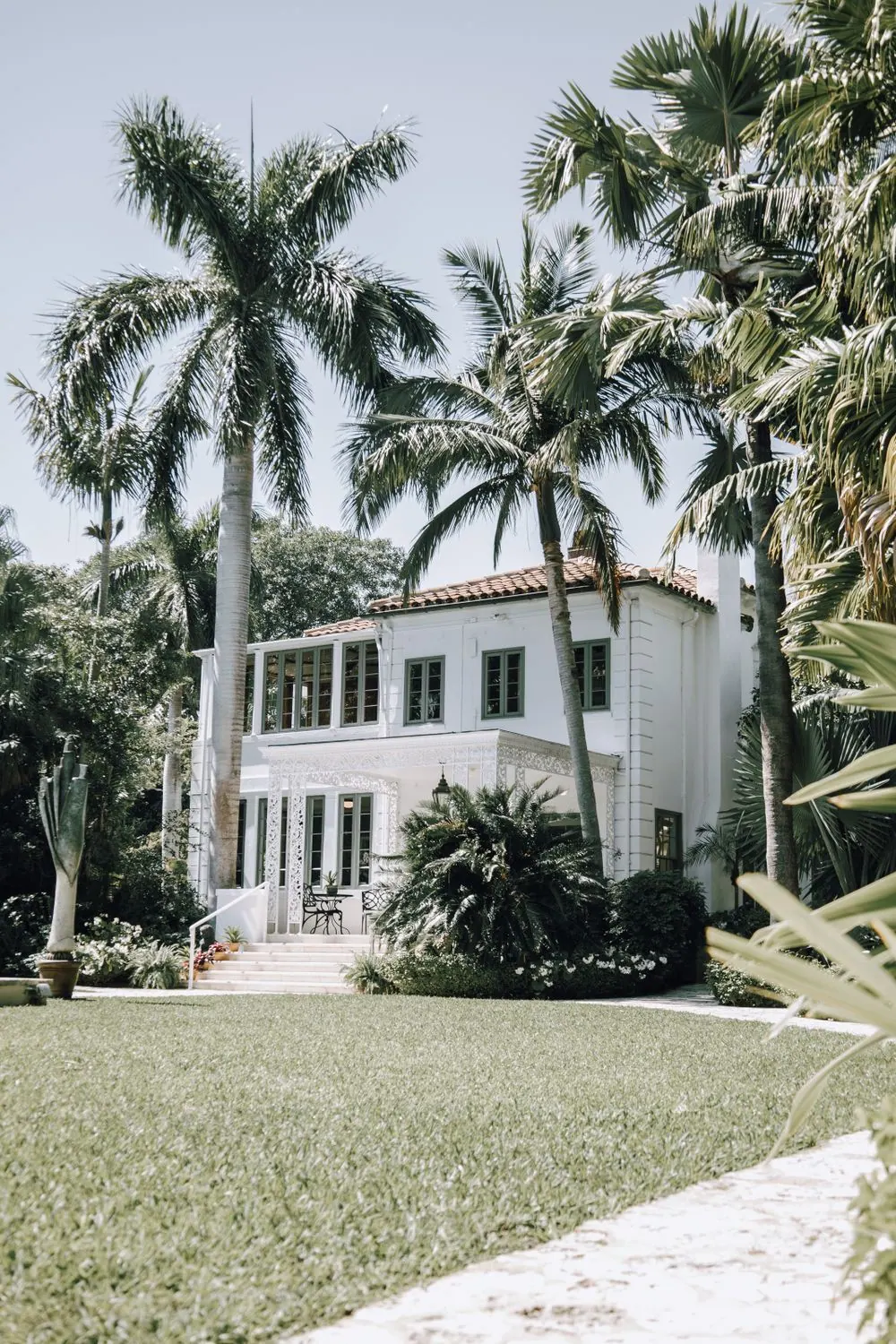 White two-story home framed by tall coconut palms