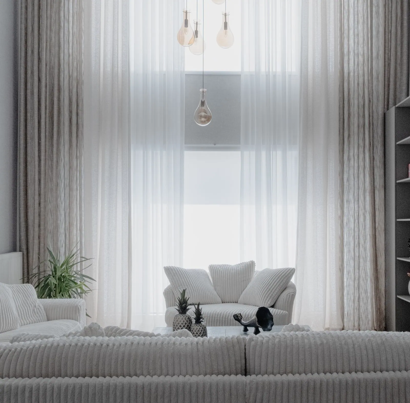 Bright living room with soft white walls, sheer curtains and pale furniture