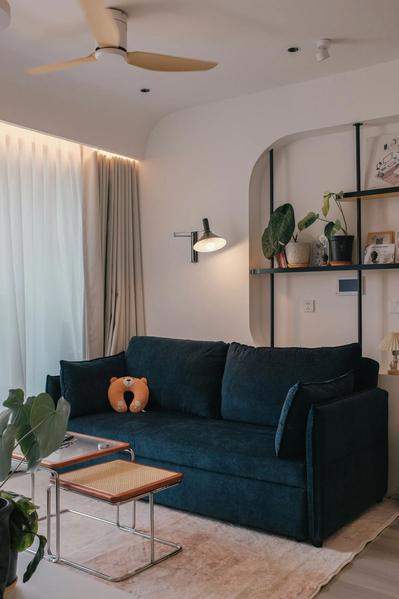 Living space with warm white walls, a navy sofa and a wood ceiling fan